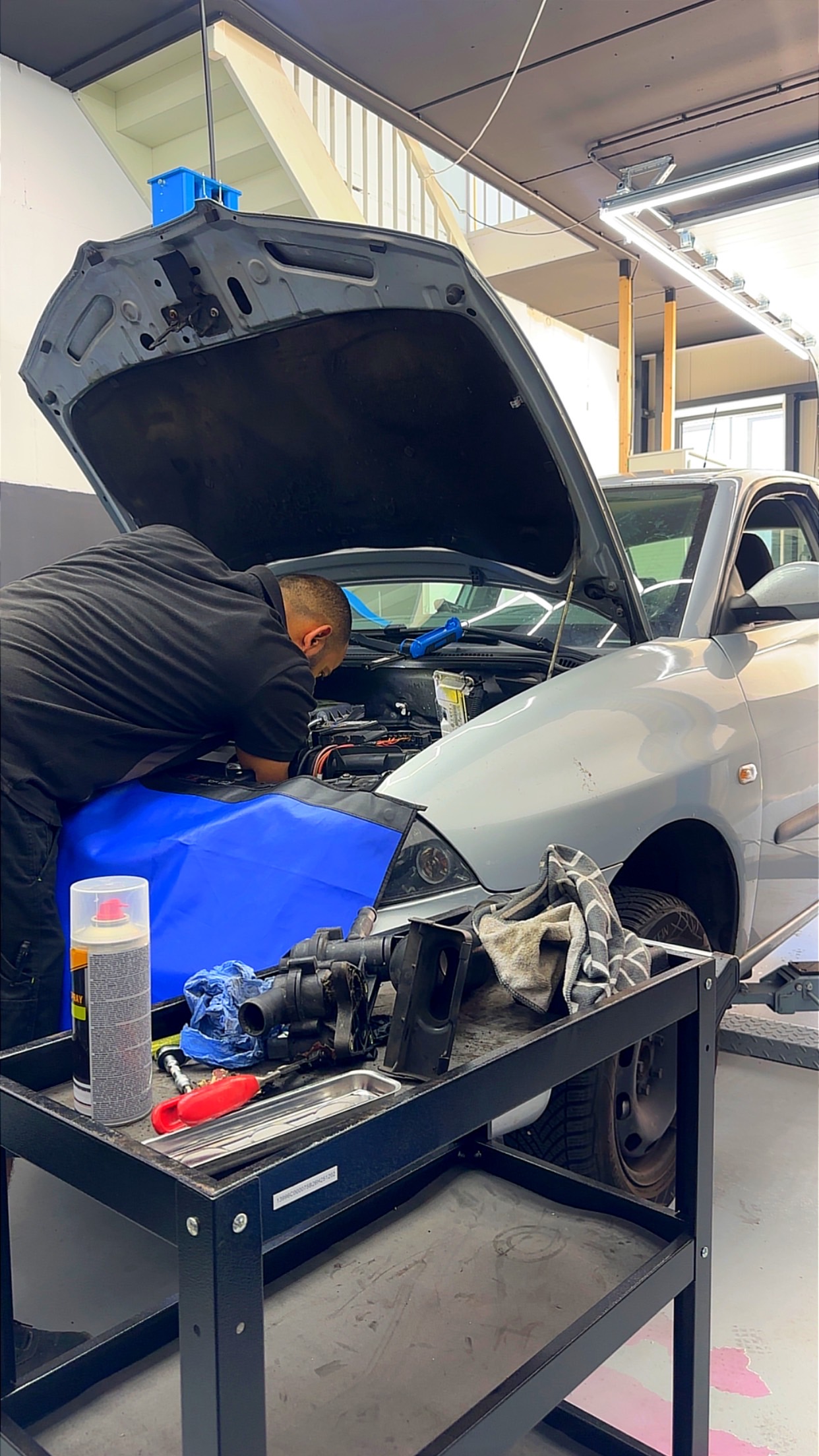 Een monteur van Auto Fixor werkt onder de motorkap